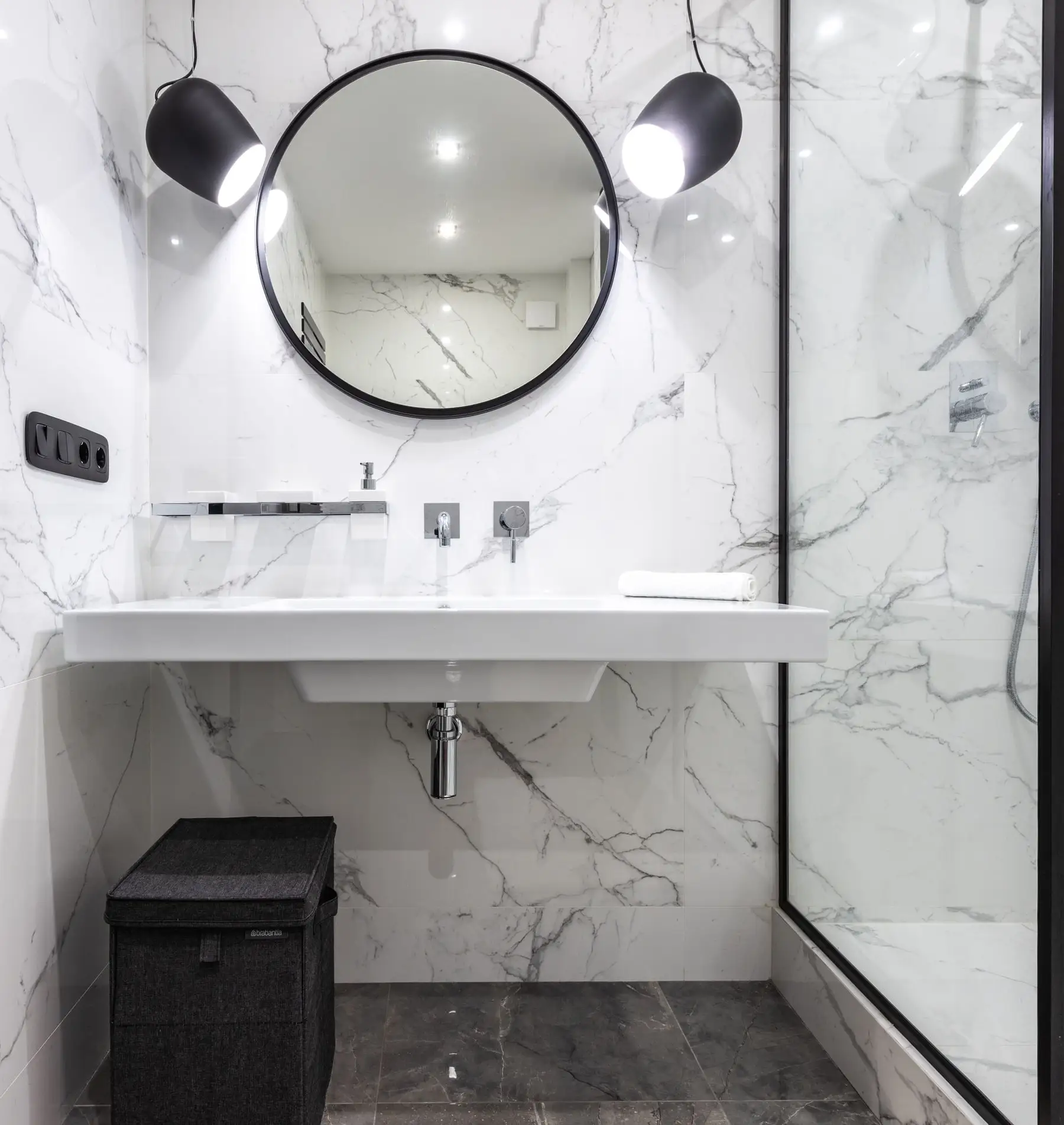 A wall-hung vanity and round mirror in a finished renovation