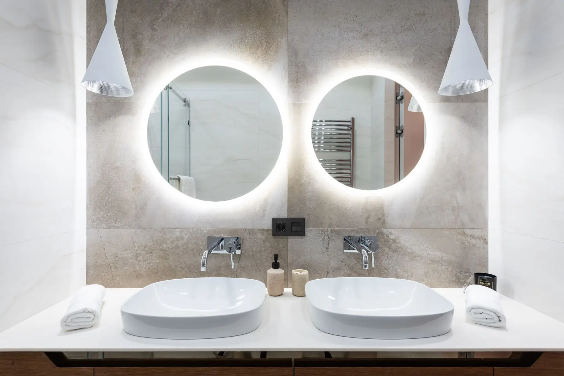 An ensuite with twin basins and backlit round mirrors